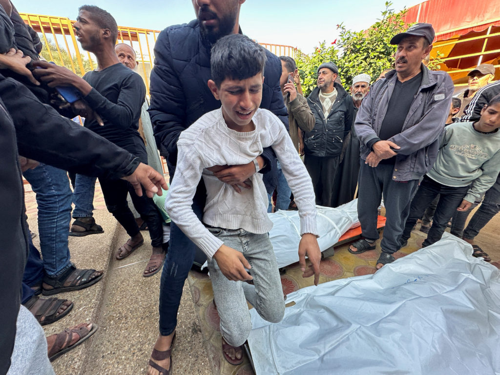 People mourn next to the body of a Palestinian killed in Israel strikes, at Nasser hospital in Khan Younis
