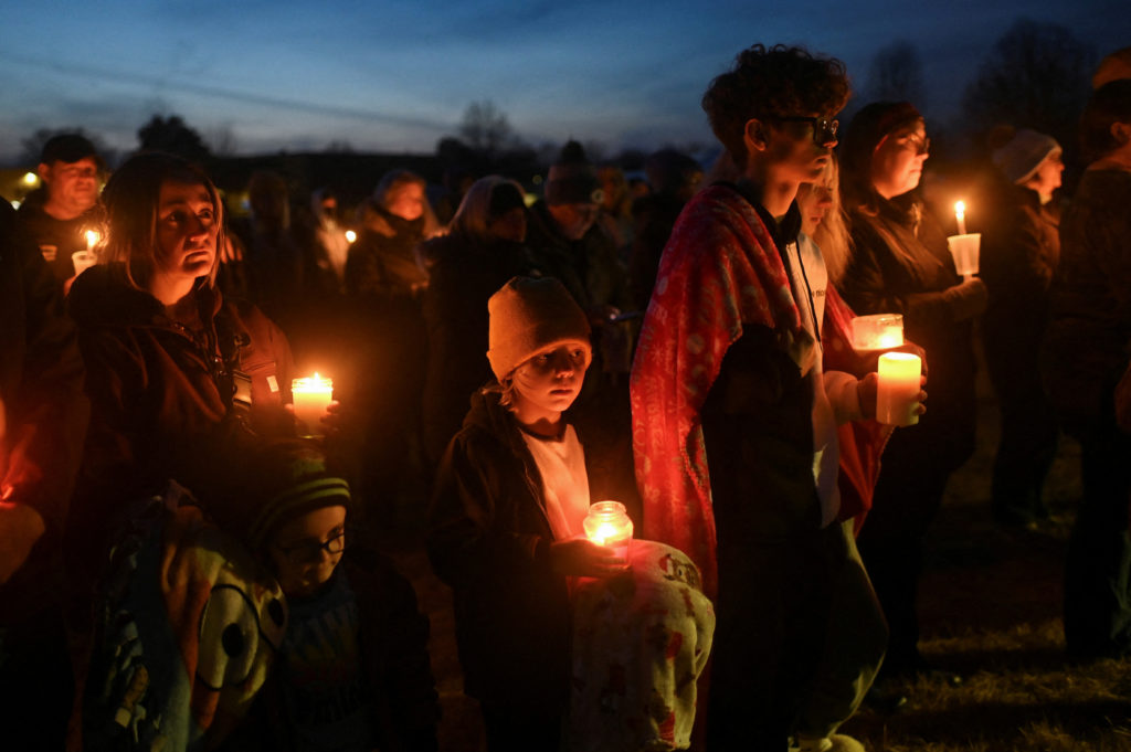 People attend a vigil after a shooting at Perry High School