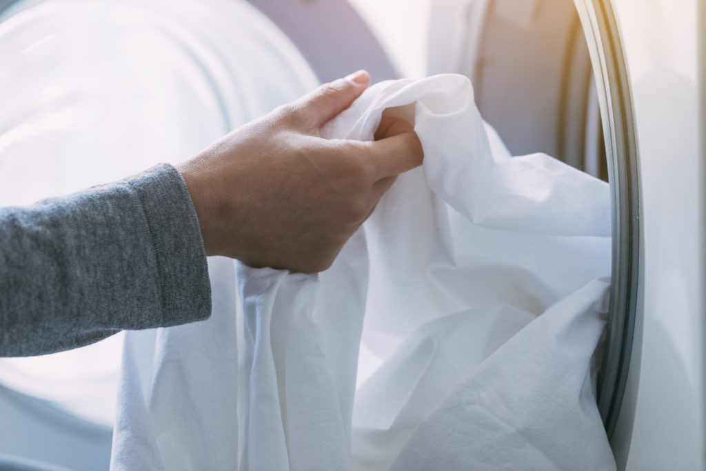 Close up of female hand dropping dirty laundry in the washing machine