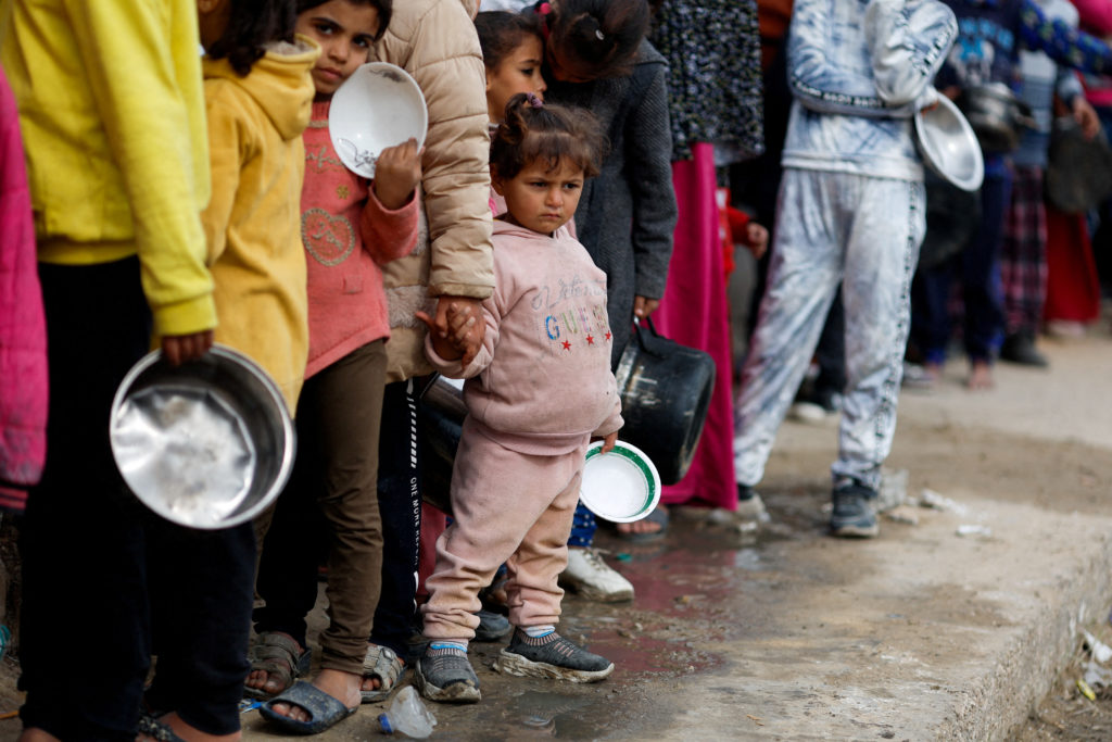 FILE PHOTO: Palestinians wait to receive food amid shortages of food supplies, in Rafah