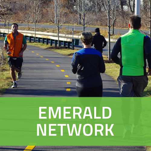 A square button with a picture of people jogging on a bike path, with the words Emerald Network in white on a green background