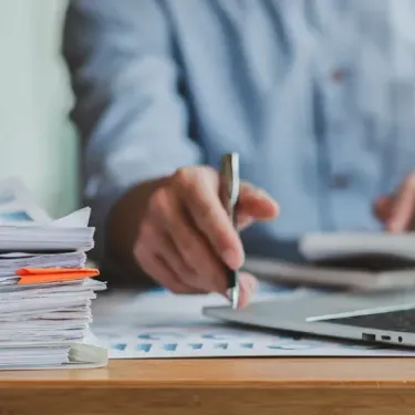 Man grading papers with pen and computer