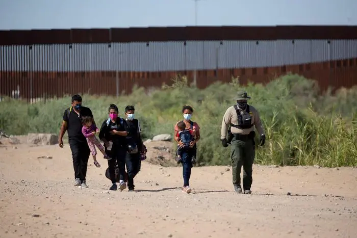 Migrantes se entregan a la patrulla fronteriza tras cruzar el muro entre México y EUA. Foto: Ringo Chiu/Shutterstock