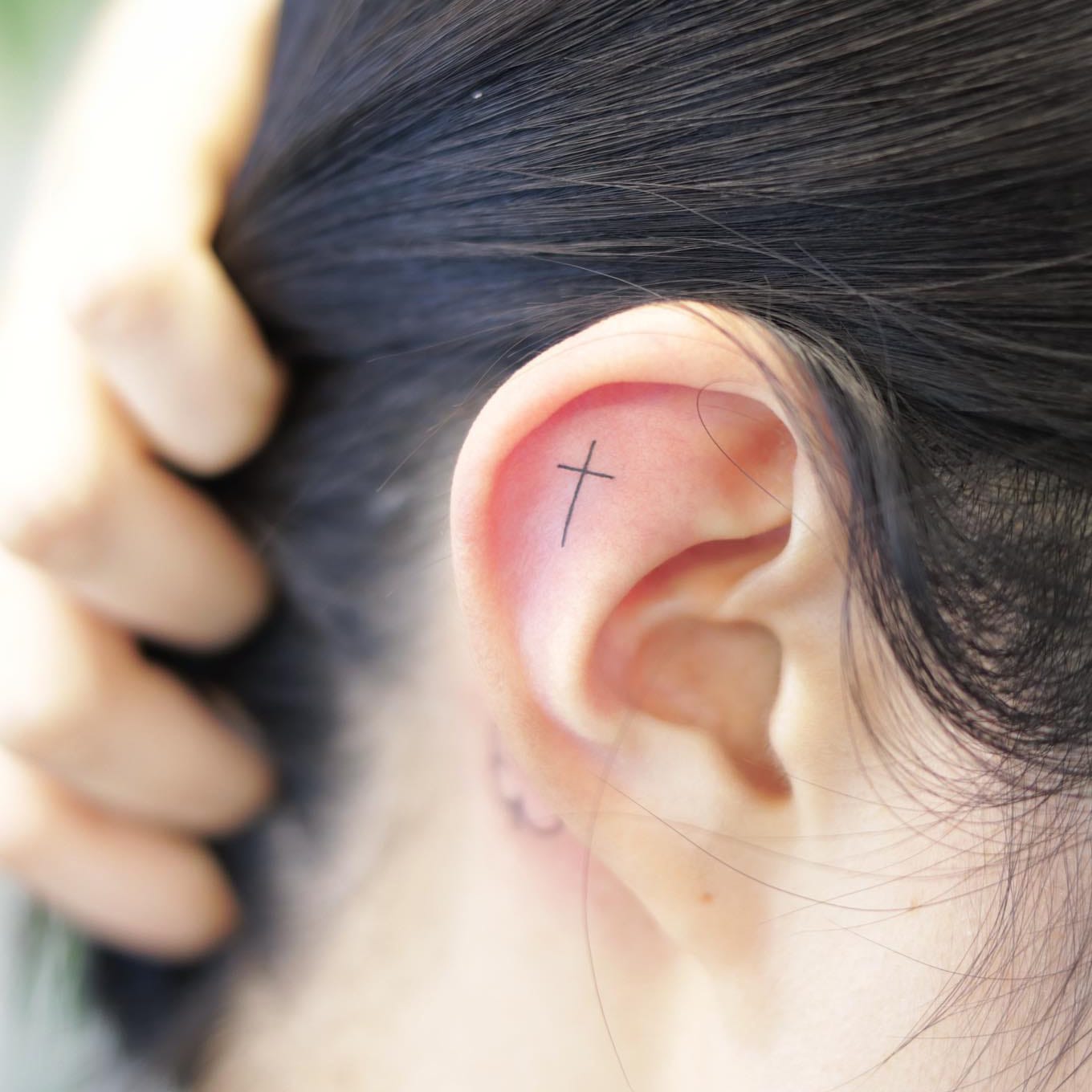 Small cross tattoo on ear
