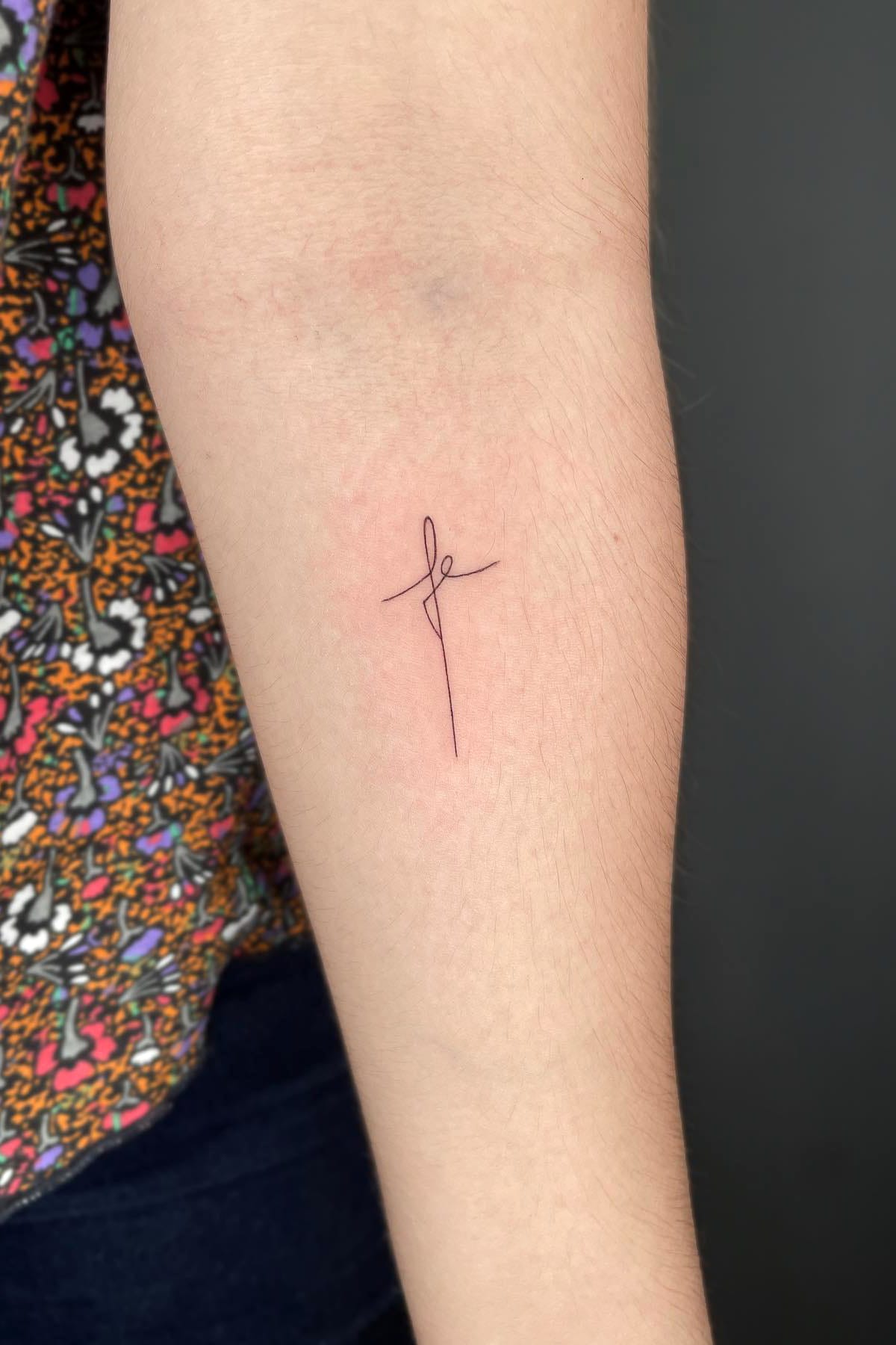 Small cross tattoo on forearm