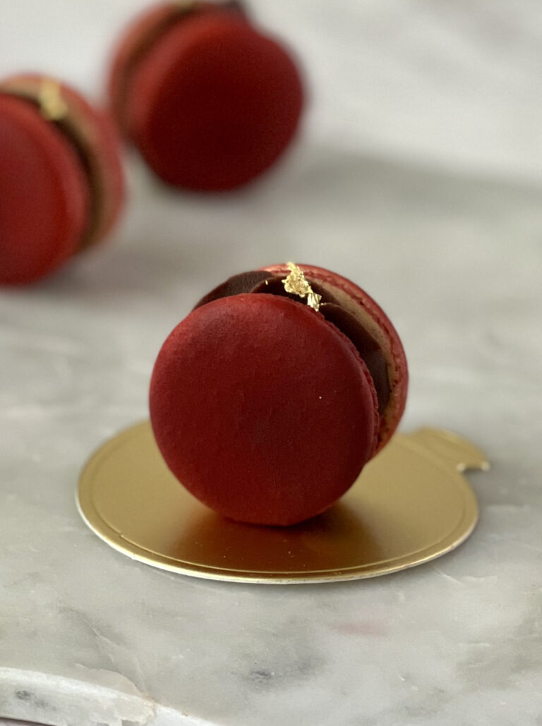 red macaron on a gold plate on a marble countertop