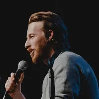 Jake Hurwitz holding a microphone in front of a black background