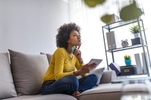  Mulher que compra on-line com o laptop em casa na sala de estar. Mulher de compras on-line. Mulher feliz, compras on-line com cartão de crédito e computador tablet.