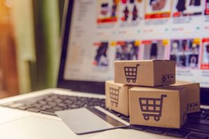 Compras on-line conceito - serviço de compras na web on-line. com pagamento por cartão de crédito e oferece entrega em domicílio. pacote ou caixas de papel com um logotipo de carrinho de compras em um teclado de laptop.