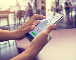  Mãos de mulher usando telefone inteligente escolher o símbolo do sorriso do rosto do ícone. Experiência no atendimento ao cliente e conceito de pesquisa de satisfação empresarial.