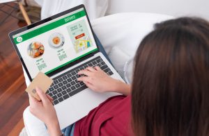 Mulher sentada, use cartão de crédito, pague por pedido de comida on-line em um laptop na página da Web de função de adicionar ao carrinho em casa, Conceito de marketing digital. Estilo de vida digital.