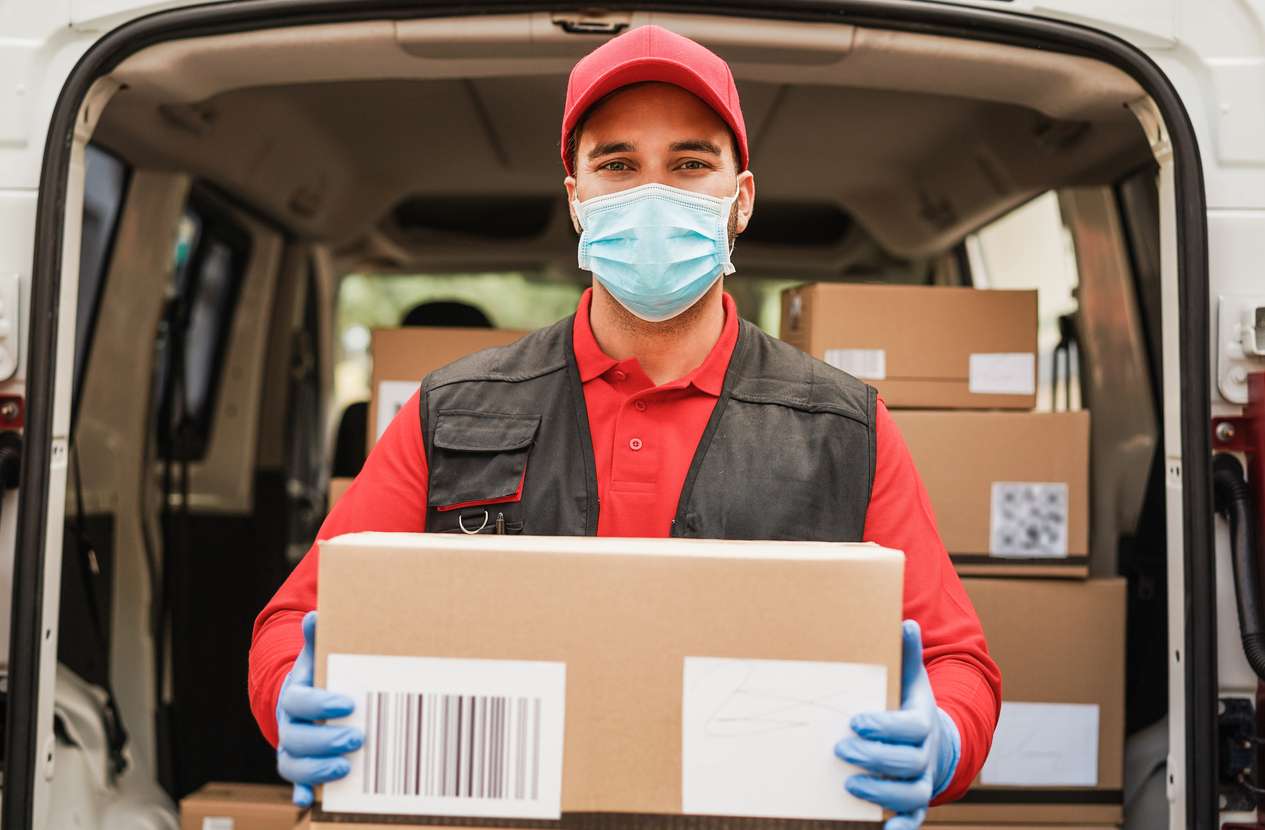  Retrato de entregador usando máscara protetora facial para prevenção da propagação do coronavírus - Correio no trabalho durante o período da pandemia. entrega para o novo cliente pós pandemia.