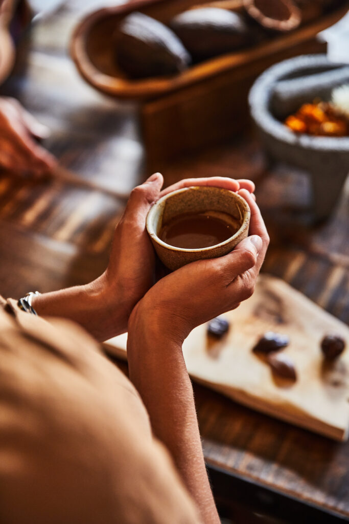 Hands holding a cup of melted chocolate, while participating in Bishops Lodge Chocolate Immersion experience