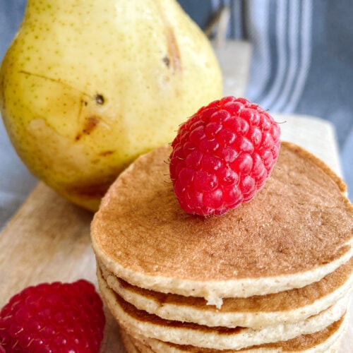 Pear pancakes served with raspberries. Pear in the background.