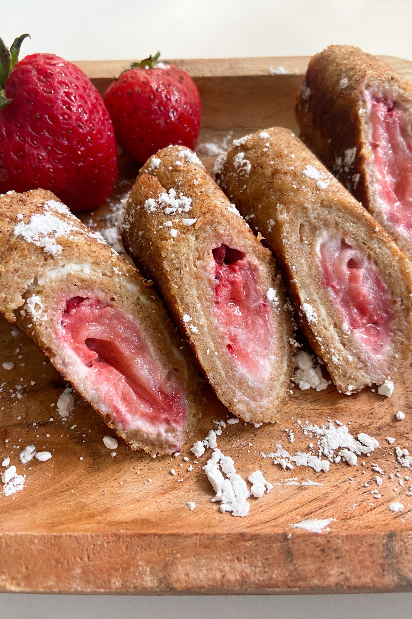Strawberry cheesecake rollups dusted with powdered sugar