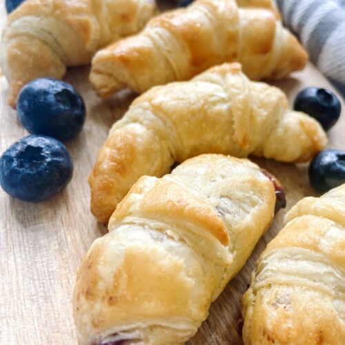 Mini blueberry croissants served on a wooden cutting board