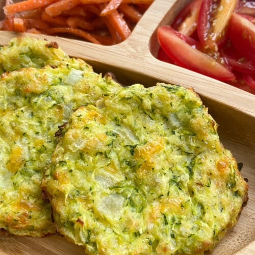 Cheesy zucchini fritters served with carrots and grape tomatoes