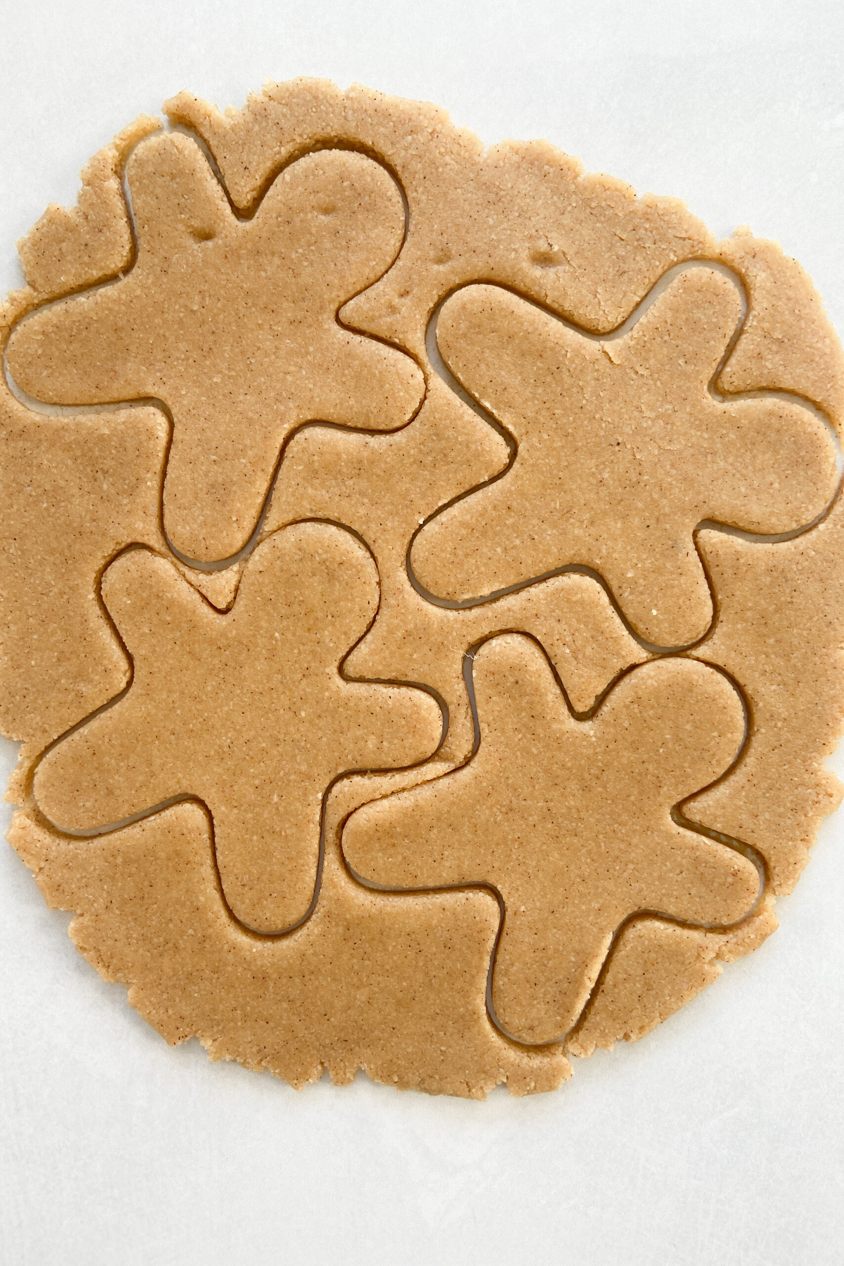 Gingerbread men being cut out of dough.