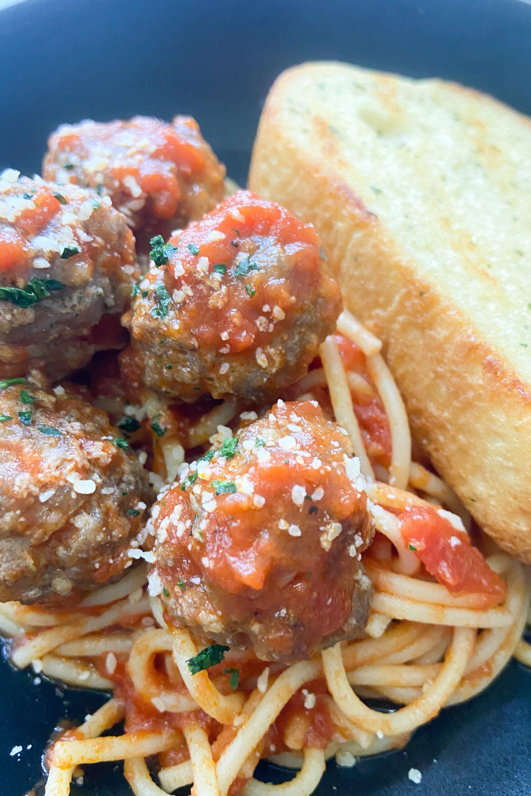 Meatballs served with spaghetti and garlic bread.