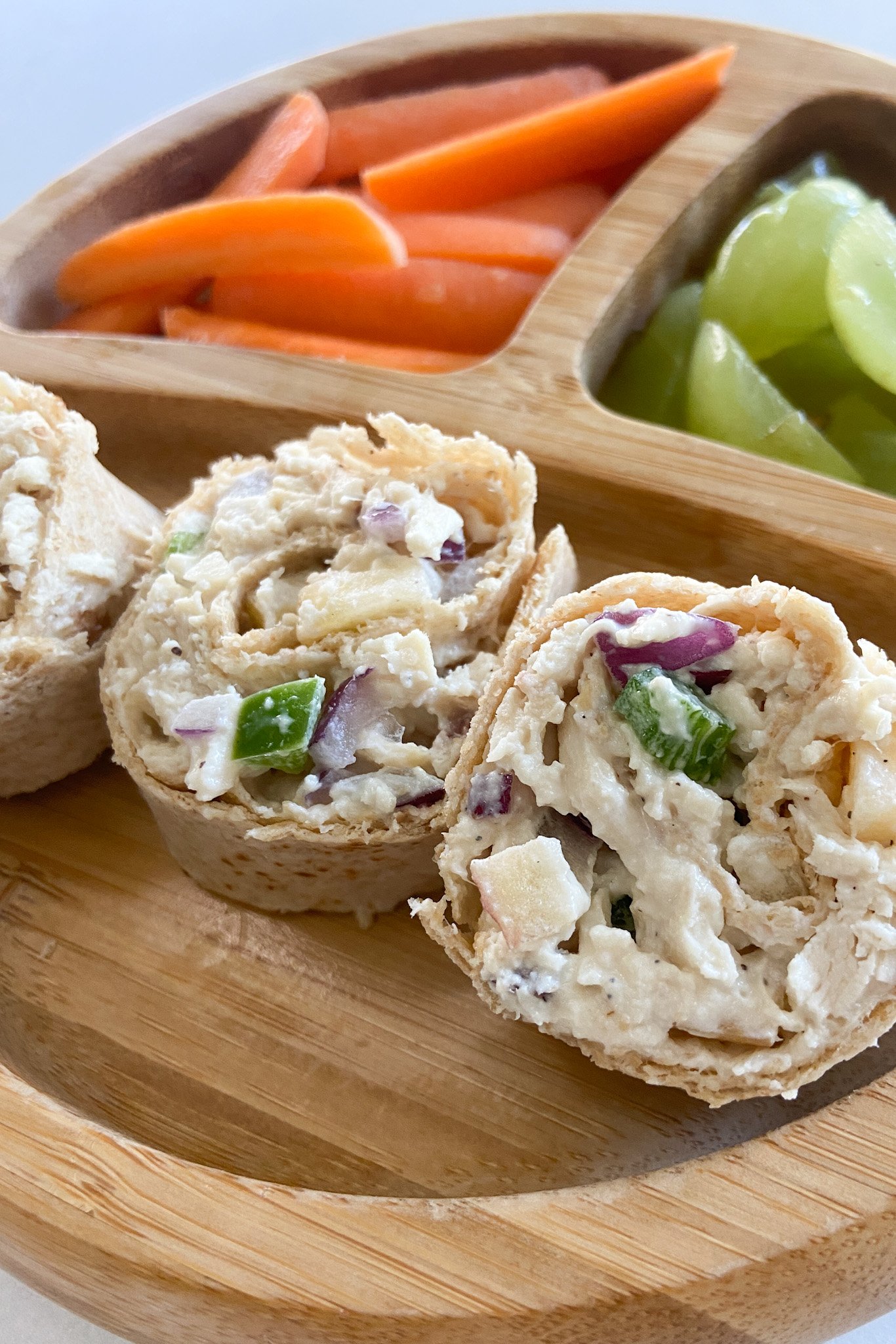 Chicken salad roll ups served with carrots and grapes.