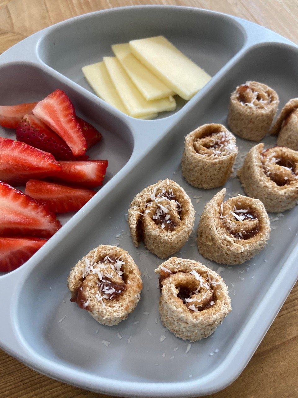Peanut butter and jelly roll ups served with strawberries and cheese.