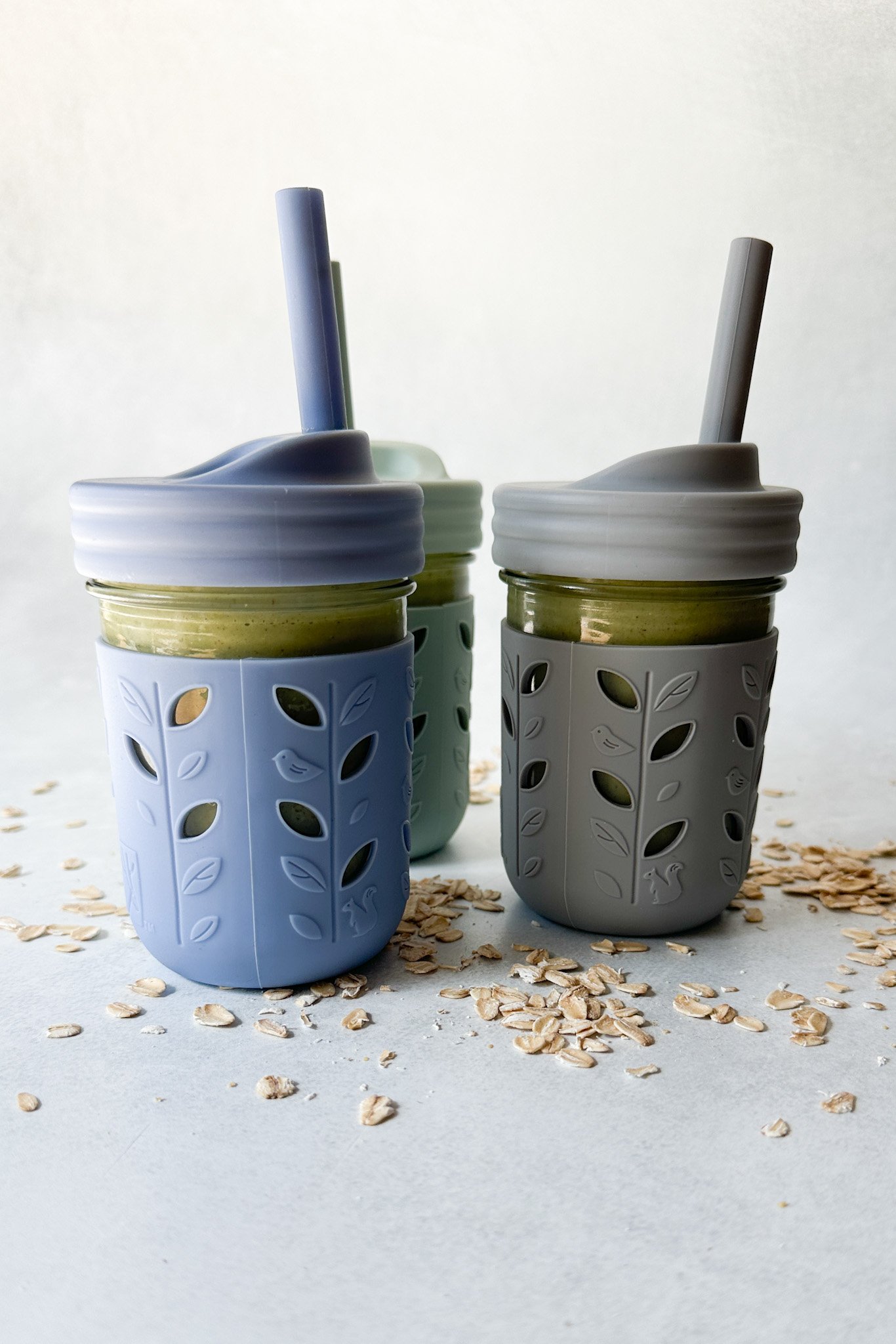 Spinach banana smoothies in toddler glass tumblers with silicone sleeves.