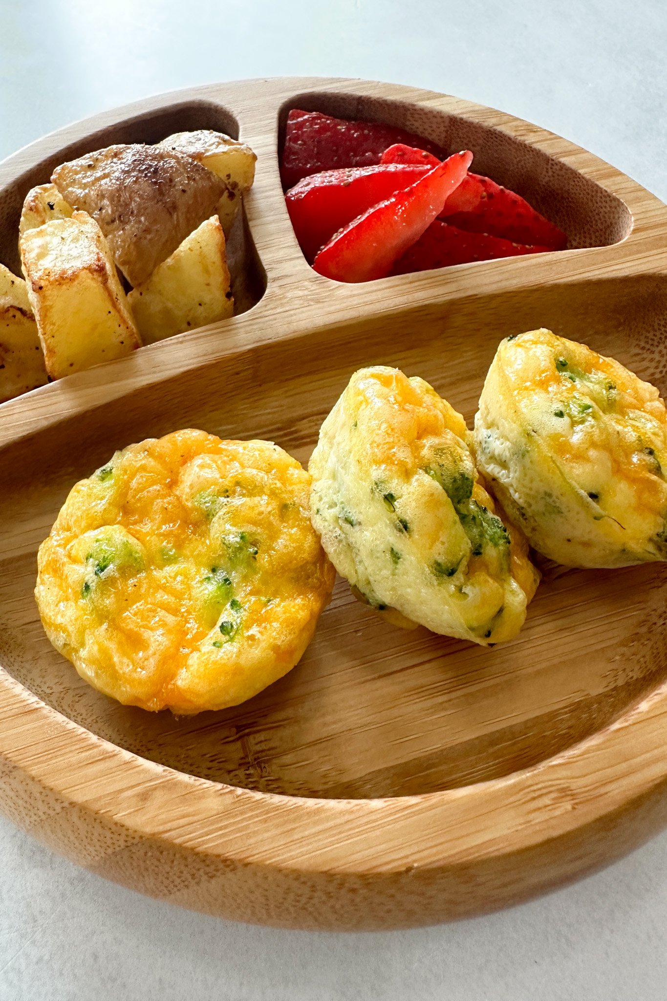Broccoli egg bites served with fruits and potatoes.