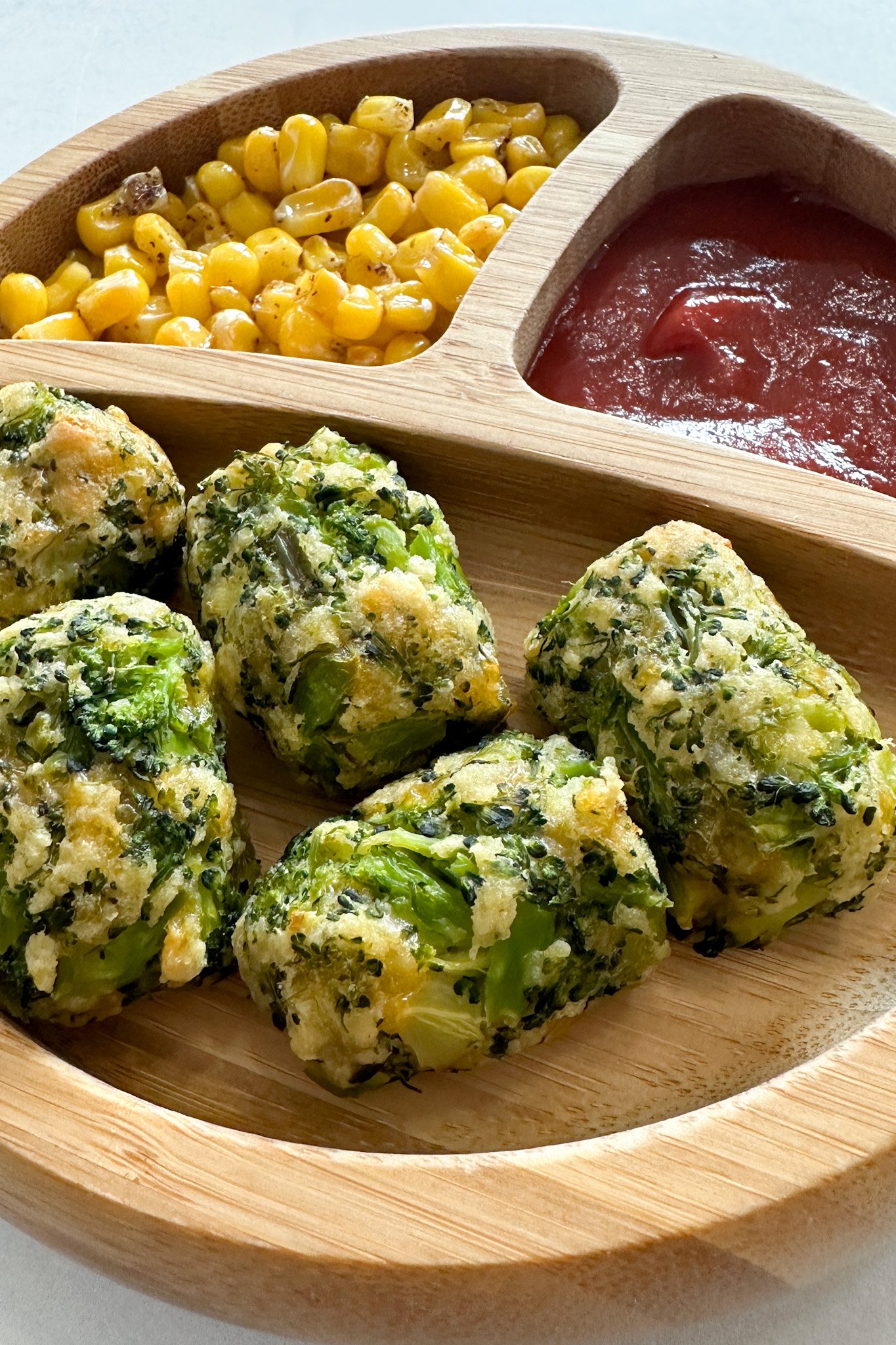 Broccoli tots served with corn and ketchup.