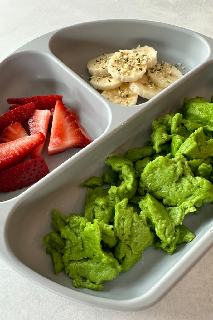 Spinach scrambled eggs served with bananas and strawberries.