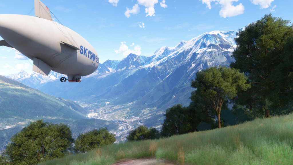 A blimp flies over a mountain valley