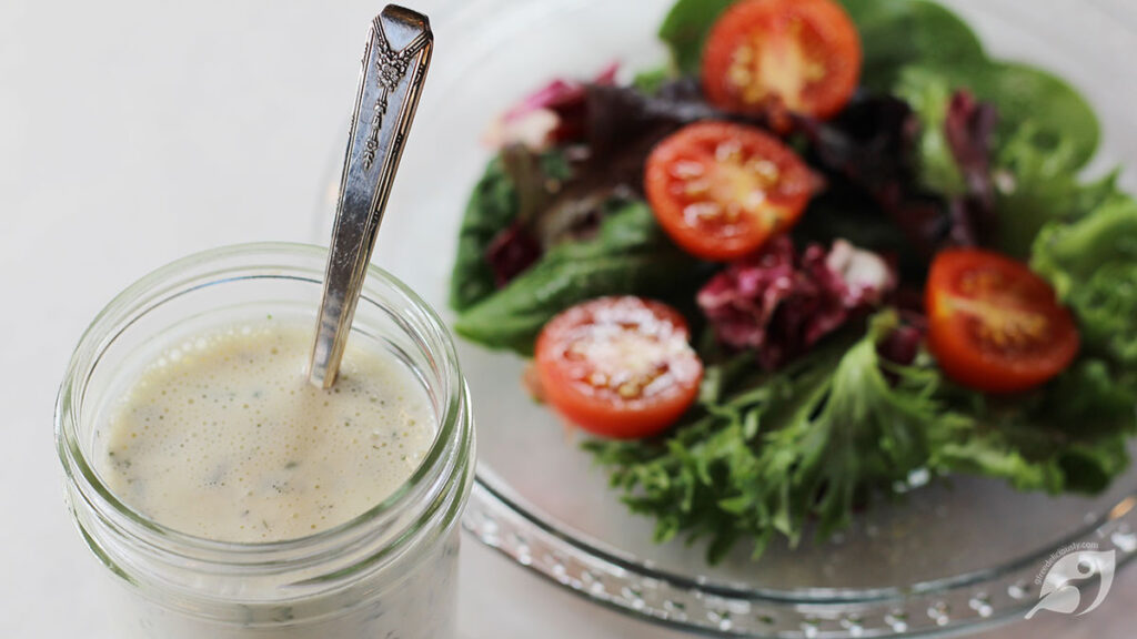 Homestyle Ranch Dressing & Dip Mix in a jar with a fresh green salad on a plate in the background.