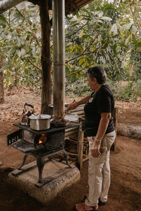 older woman roasting cacao pods on a stove on a costa rica chocolate tour