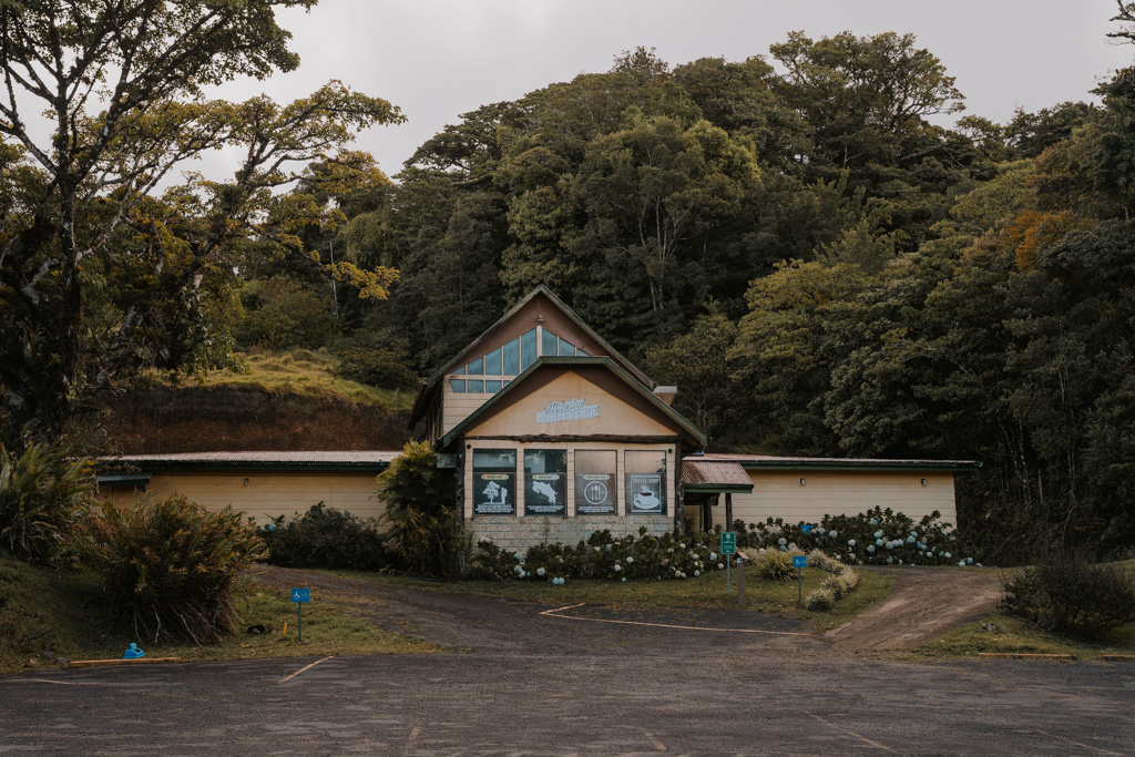 large yellow brick building with vaulted roof and paved parking spaces at Monteverde Cloud Forest Reserve