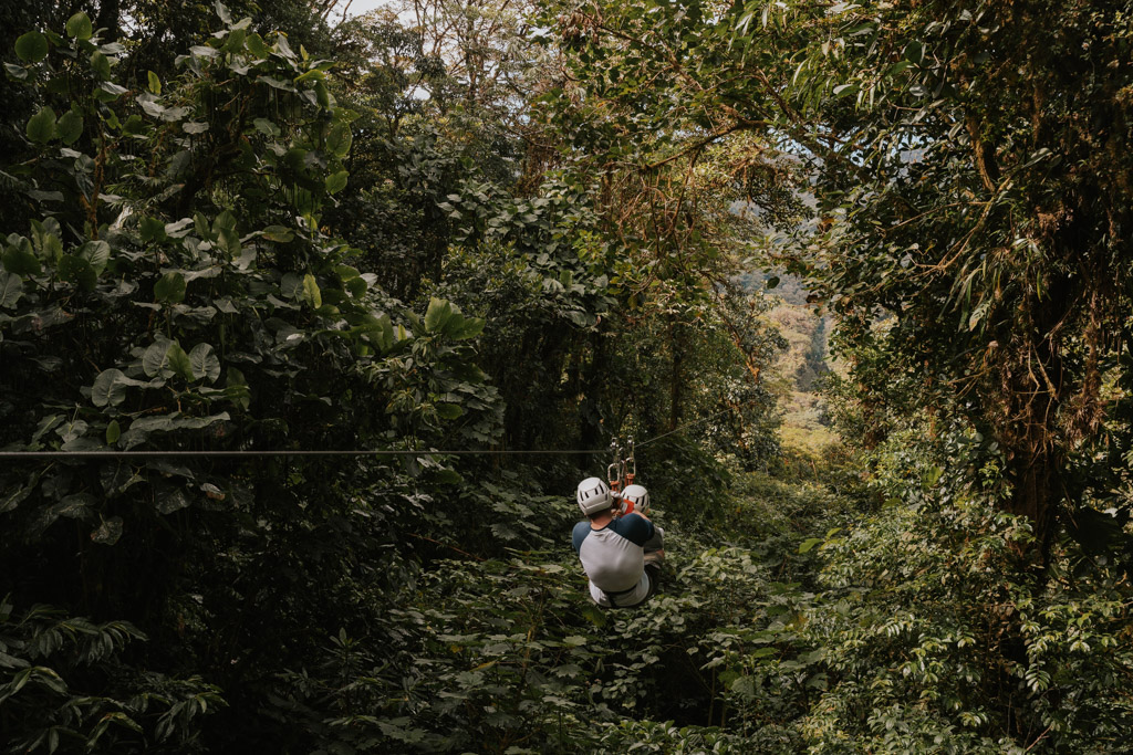 two adults tandem ziplining among the Selvatura Park rainforest 