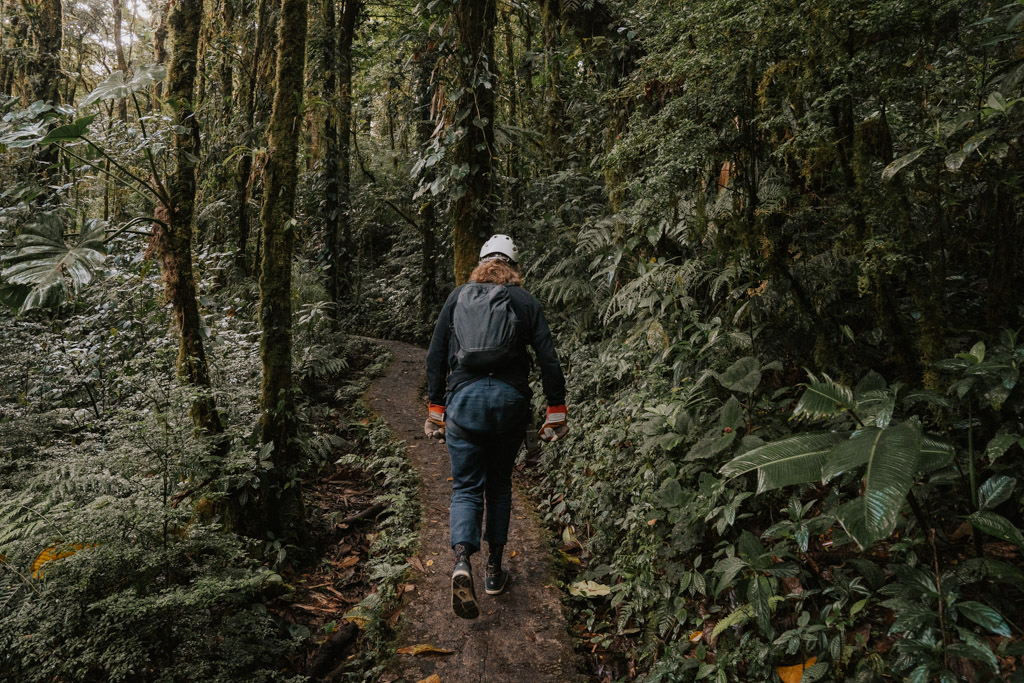 man in Monteverde zipline gear walking up a forested path