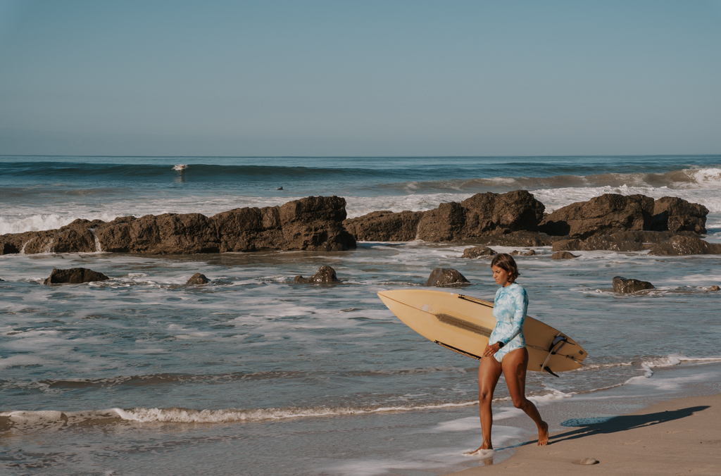 woman walking with her surfboard at playa santa teresa