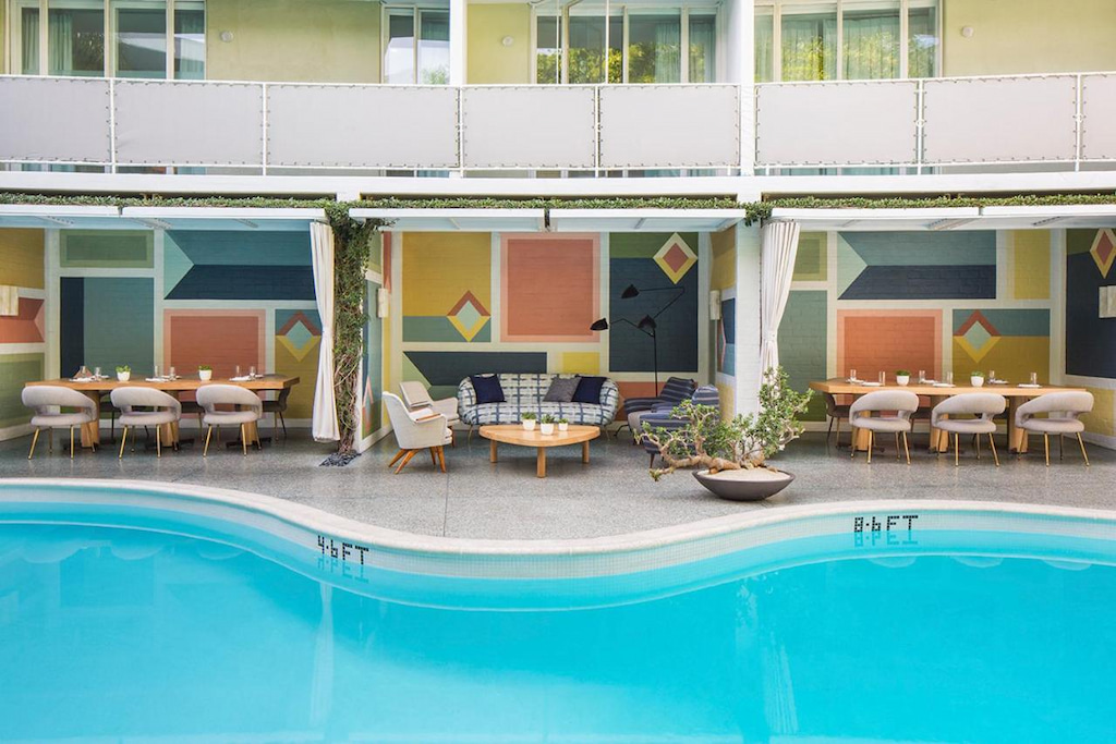 midcentury modern poolside lounge furniture with balcony and bright blue pool at boutique Beverly Hills hotel