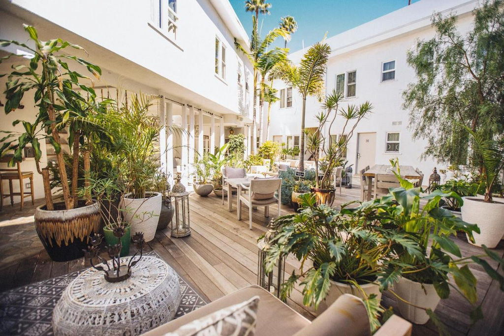the courtyard of one of the best boutique hotels Beverly Hills has with greenery throughout and beachy furniture