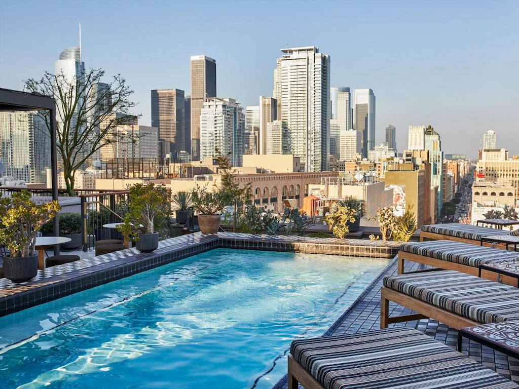 Boutique hotel in Downtown Los Angeles rooftop pool with loungers overlooking tall buildings