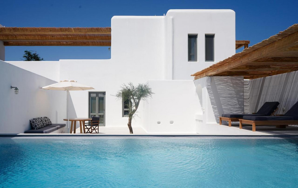 bright blue swimming pool infront of Cycladic square Naxos boutique hotel with umbrella and sub loungers