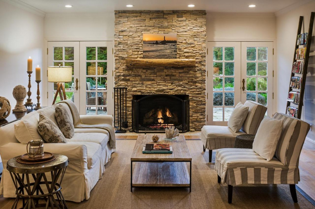 A fireplace in one of the luxury rooms in Seal Cove Inn surrounded by white and gray chairs in one of the cool hotels in Northern California.