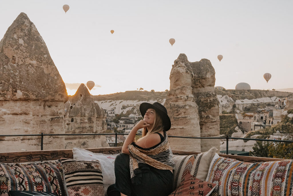 girl with black hat enjoying the comfortable seating and view of the hot air balloons at her Cappadocia view hotel