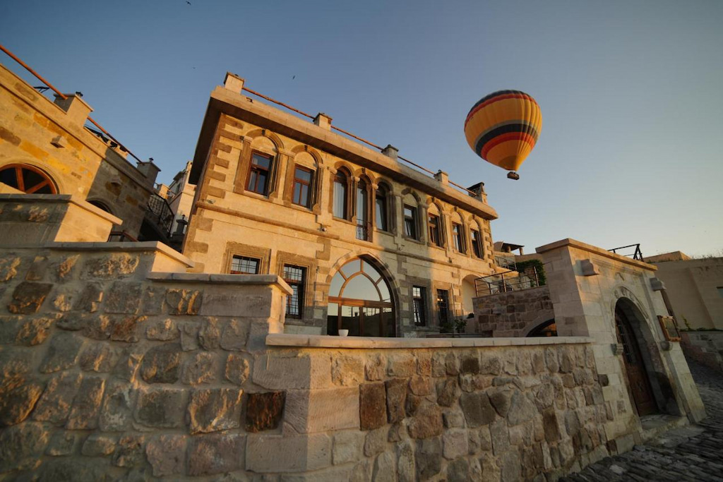 a single orange striped balloon overhead a two story hotel in Cappadocia at dawn