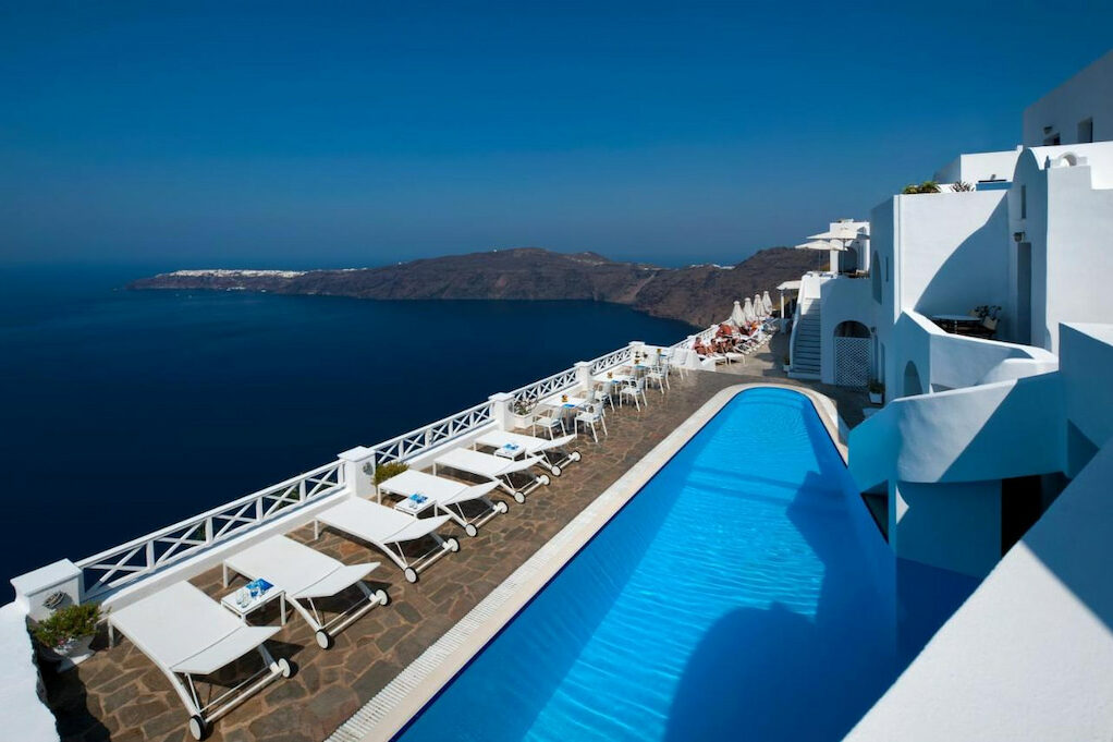 A modern-designed pool beside benches with wheels that has an amazing view of the Aegean Sea.