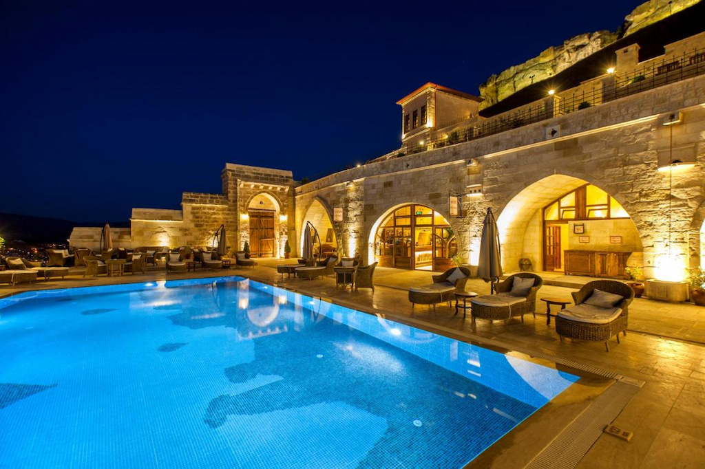 large lighted pool in best hotel in Cappadocia Uchisar with arched stone details and sun loungers