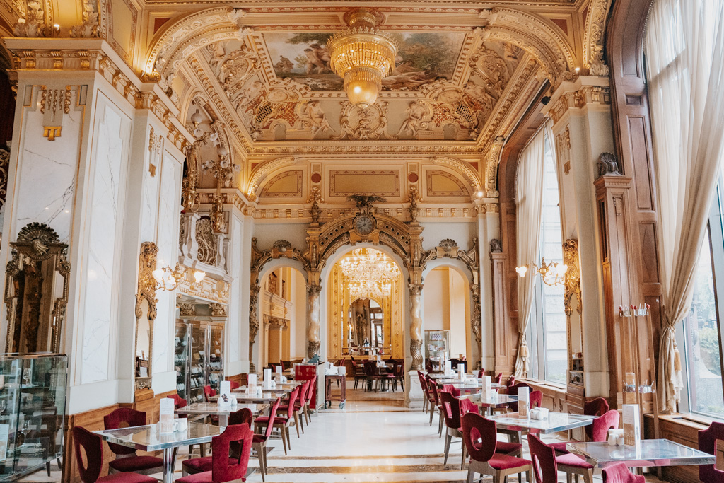 exquisite ornate interiors of the New York Cafe Budapest dining room with red chairs