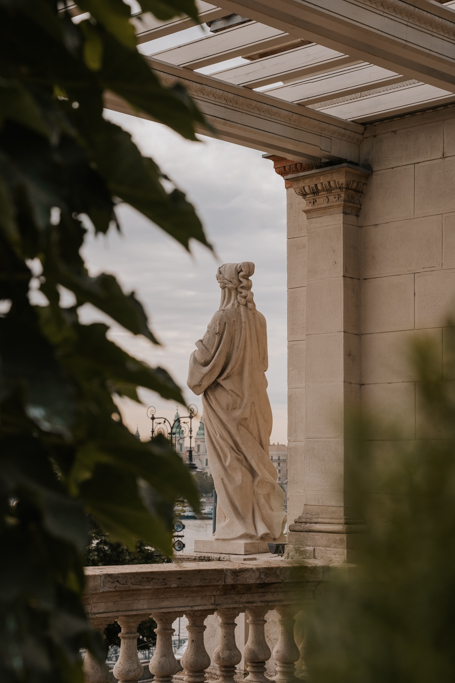 stone statue of a woman through greenery in Buda Castle District