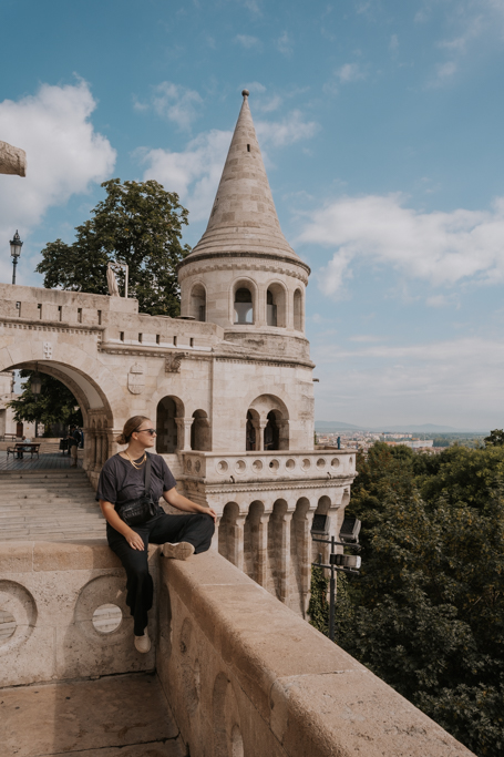 a girl wearing black perched on the ornate Fisherman's Bastion in Buda Castle district where to stay in Budapest for first timers and couples