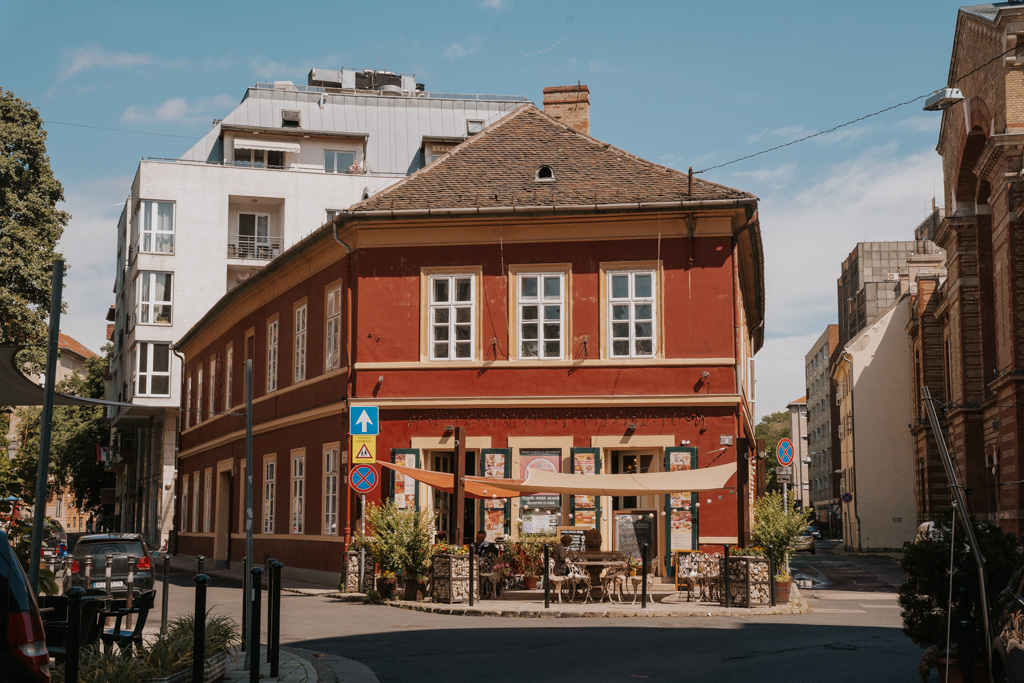 historic red painted building with awning and streetside chairs in Budapest best area to stay