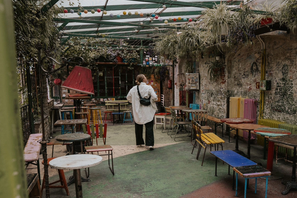 woman in white top and black pants exploring the intricate interiors of the ruin bars in Budapest Jewish Quarter